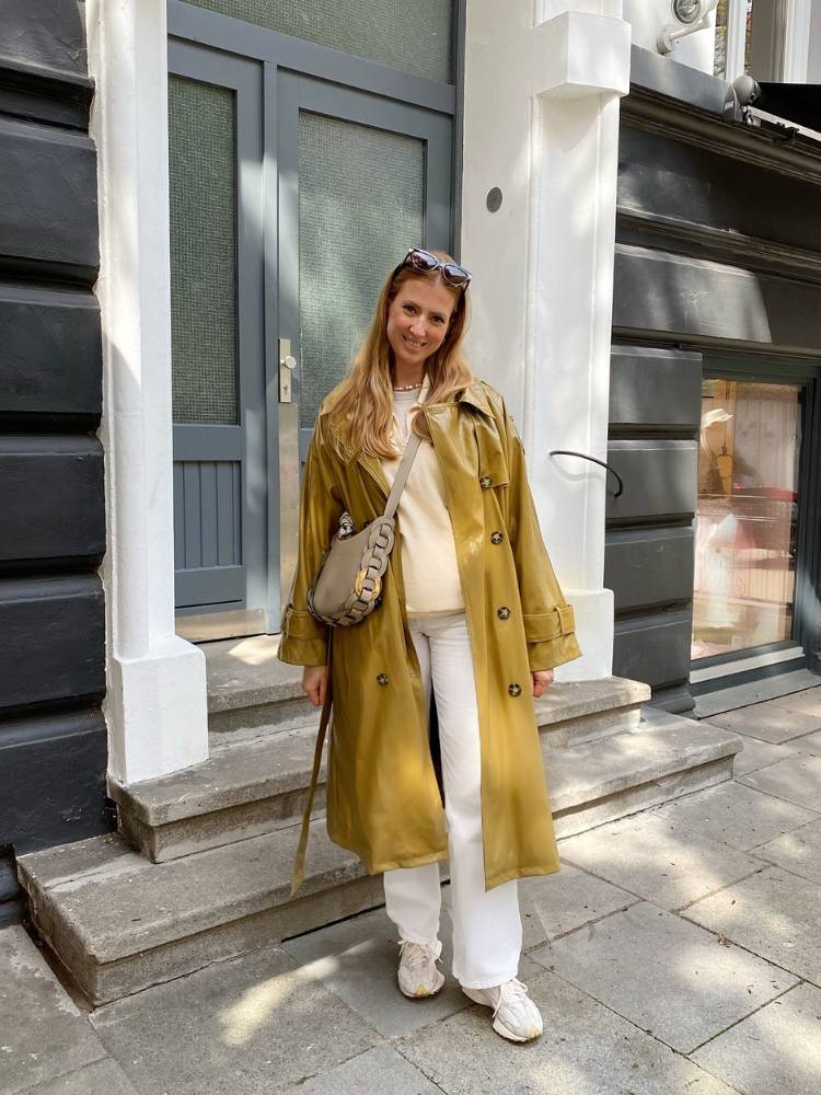 Mulher de pele clara usado blusa bege, calça bege e trench coat mostarda