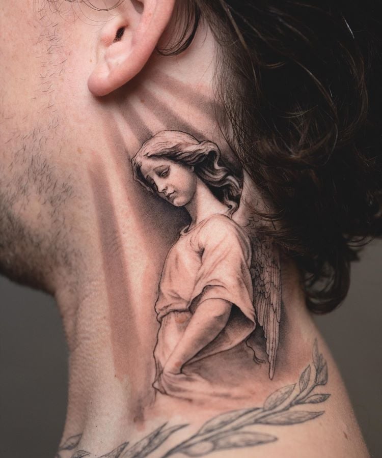 A imagem mostra uma pessoa de perfil com cabelo escuro e ondulado. Ela tem uma tatuagem no pescoço de um anjo em tons de cinza, com asas detalhadas e expressão serena. A tatuagem cobre a lateral do pescoço, desde a orelha até a clavícula, com grande realismo.