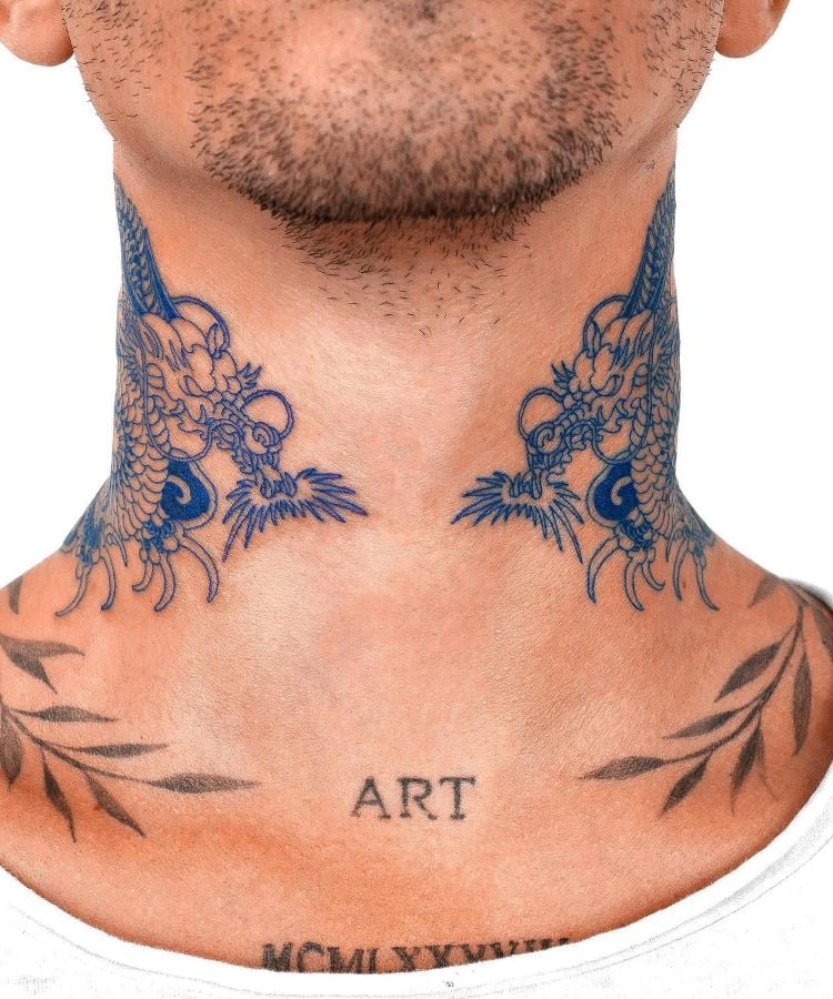 A imagem mostra uma pessoa com uma tatuagem no pescoço de dois dragões azuis, um de cada lado, cujas cabeças se encontram na frente. A pessoa tem barba rala e a palavra "ART" tatuada na parte inferior do pescoço.