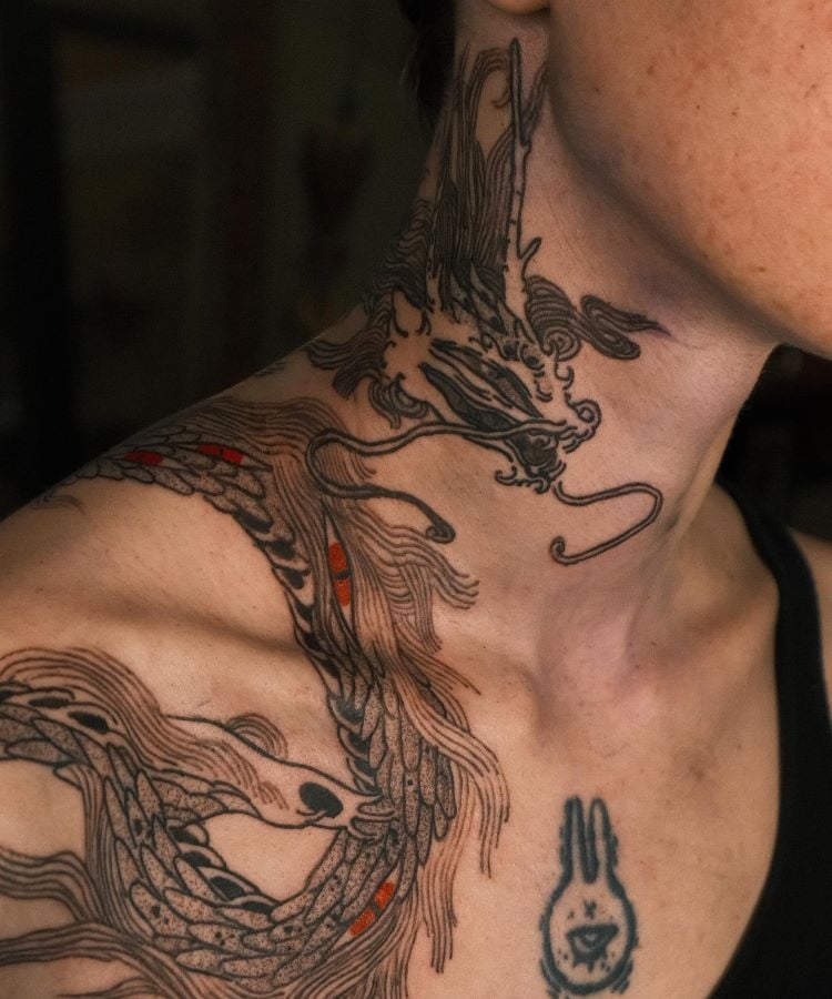 A imagem mostra uma pessoa com barba e cabelo curto. Ela tem uma tatuagem no pescoço de um dragão em preto e vermelho. A tatuagem cobre a lateral do pescoço, com detalhes intricados e sombreados, criando um efeito dramático e impressionante.