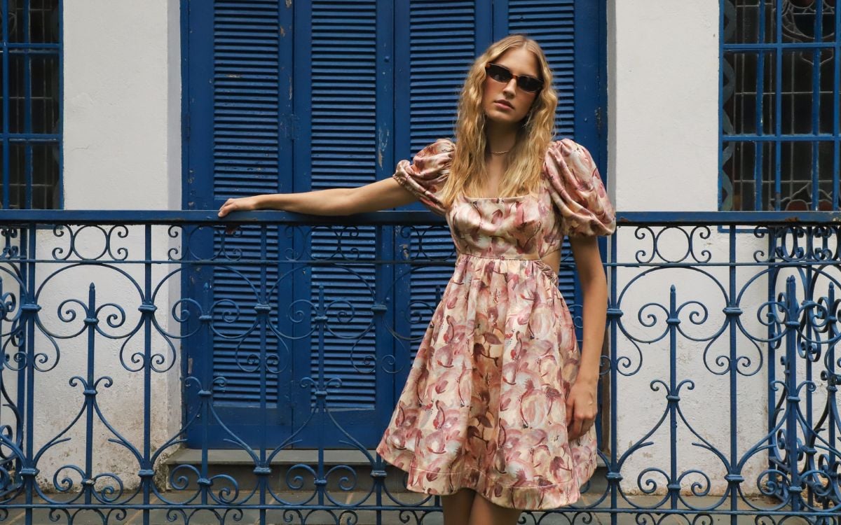 Foto de mulher loira usando vestido curto florido com mangas bufantes da coleção Aurora da Inglesis