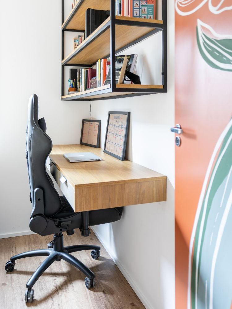 Home office pequeno decorado com armário aéreo, escrivaninha de madeira e cadeira ergonômica preta