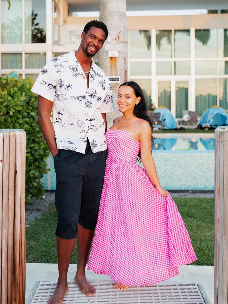 Chris Bosh usando blusa branca e bermuda preta ao lado de Adrienne Wiliams usando vestido midi rosa 