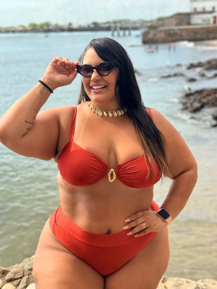 Mulher de pele clara usando biquíni laranja com argola dourada no top