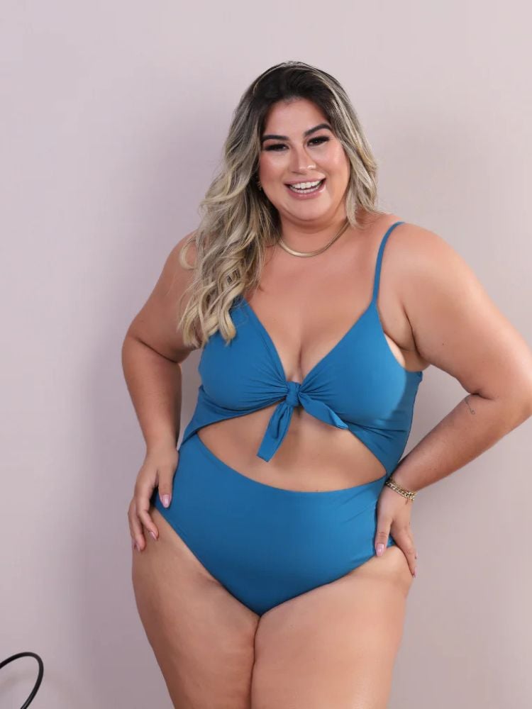 Mulher de pele clara usando maiô azul celeste com nó nos seios e recorte na barriga 