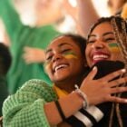 Foto de 2 mulheres abraçadas com o rosto pintado de verde e amarelo. Elas são torcedoras do Brasil nas Olimpíadas 2024. Tudo sobre quando acabam as Olimpíadas 2024