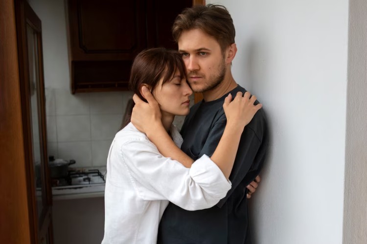 Foto de homem de pele clara com expressão triste abraçado com mulher de pele clara também abalada