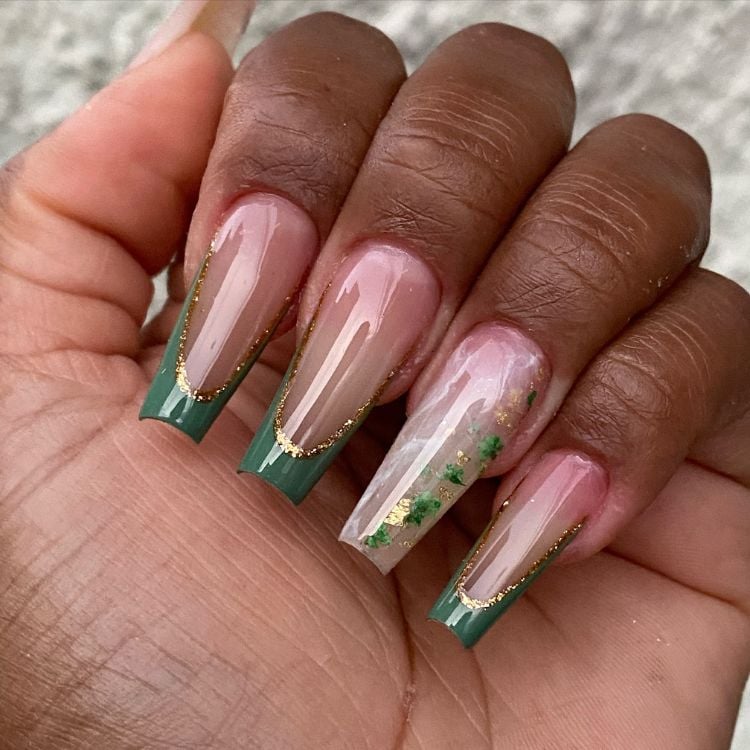 Mão de pessoa de pele negra com unhas ballerina com francesinha verde e brilho encapsulado 