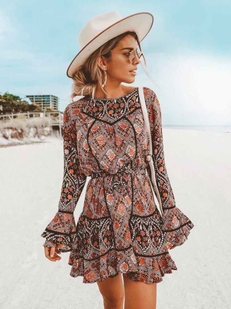 Mulher de pele clara usando chapéu, bolsa transversal, óculos de sol e vestido boho chic com babados