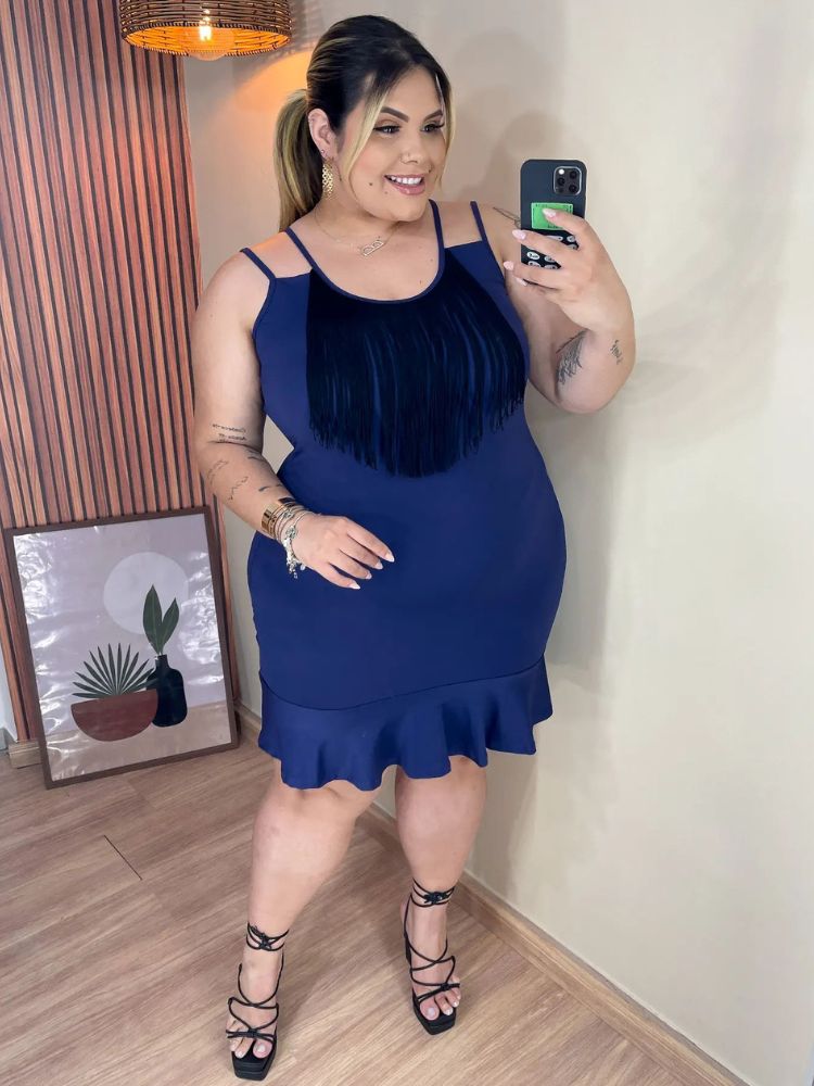 Mulher de pele clara usando vestido curto azul com franjas pretas no decote e salto alto