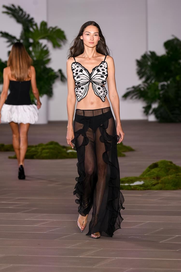 Modelo usando top de borboleta e calça preta no desfile de PAtBO na NYFW