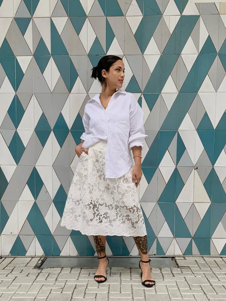 Mulher de pele clara usando camisa branca de algodão e saia midi bege de renda