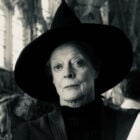 A imagem mostra a atriz Maggie Smith usando um chapéu pontudo, típico de uma bruxa, em um ambiente que parece ser uma construção antiga com grandes janelas ao fundo. A expressão facial é séria e a imagem está em preto e branco, o que dá um ar clássico e misterioso à cena.