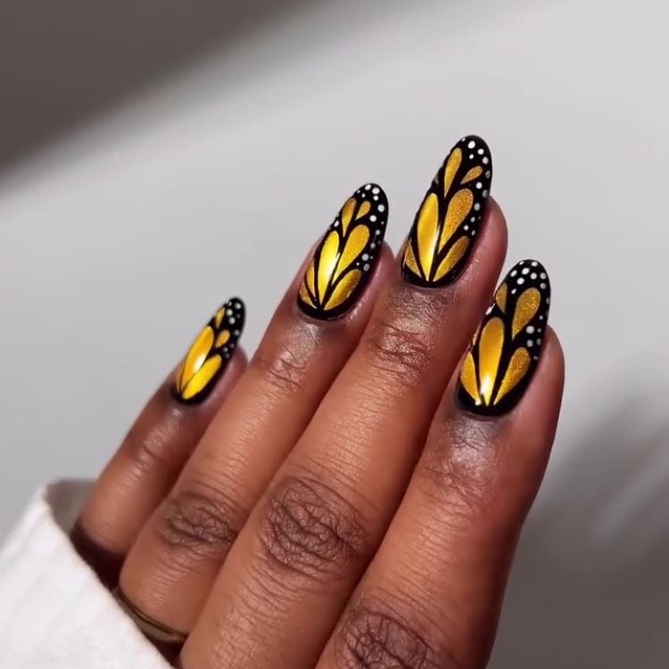 Unhas finalizadas com design de borboleta, prontas e brilhantes.