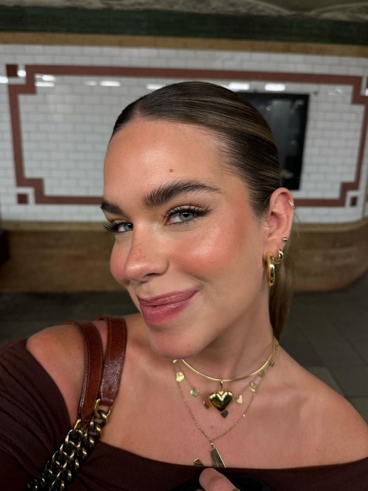 Mulher de pele clara tirando selfie com rosto em 45 graus e sorrindo 