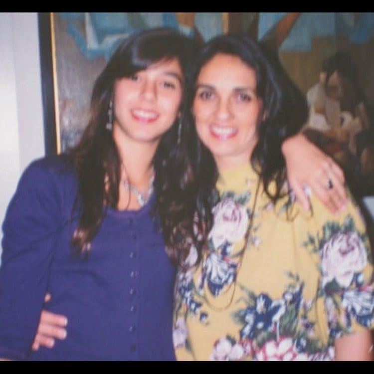 Foto antiga de Priscila usando blusa azul, abraçada com a mãe, Jovita, que usa roupa amarela e azul 