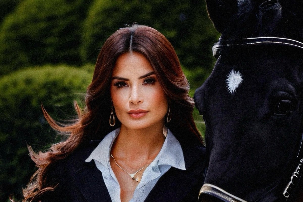 Vanessa Carvalho usando camisa branca com blazer preto, posando ao lado de cavalo preto