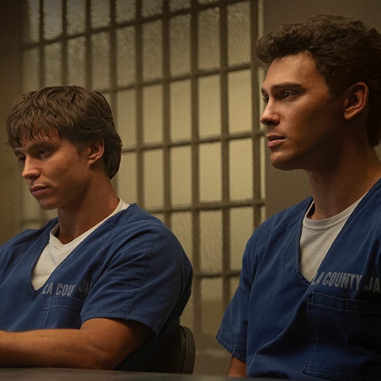 Cena da série em que os irmãos estão sentados à mesa usando uniforme azul da penitenciária 