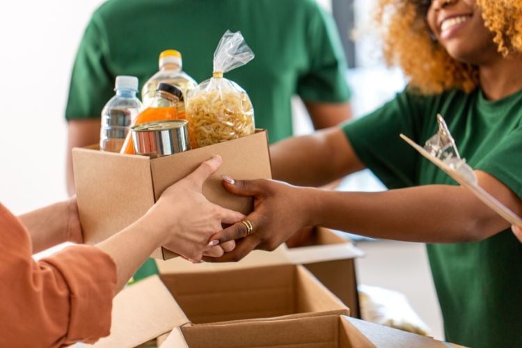 Mãos de pessoas segurando caixas com alimentos para doação 