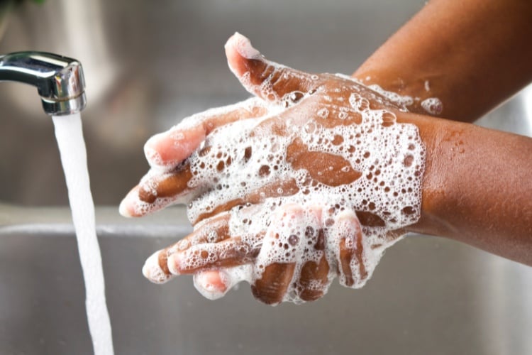 Pessoa de pele negra lavando as mãos com sabonete 