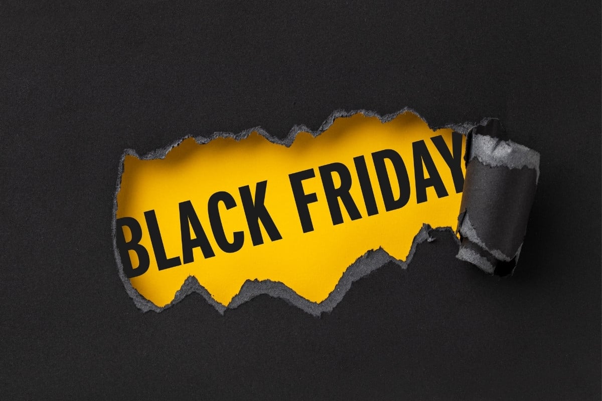 A imagem mostra um fundo preto com uma parte rasgada, revelando um papel amarelo por baixo. No centro, em letras grandes e pretas, está escrito "BLACK FRIDAY". O efeito de papel rasgado cria uma sensação de descoberta ou surpresa, destacando a mensagem promocional.