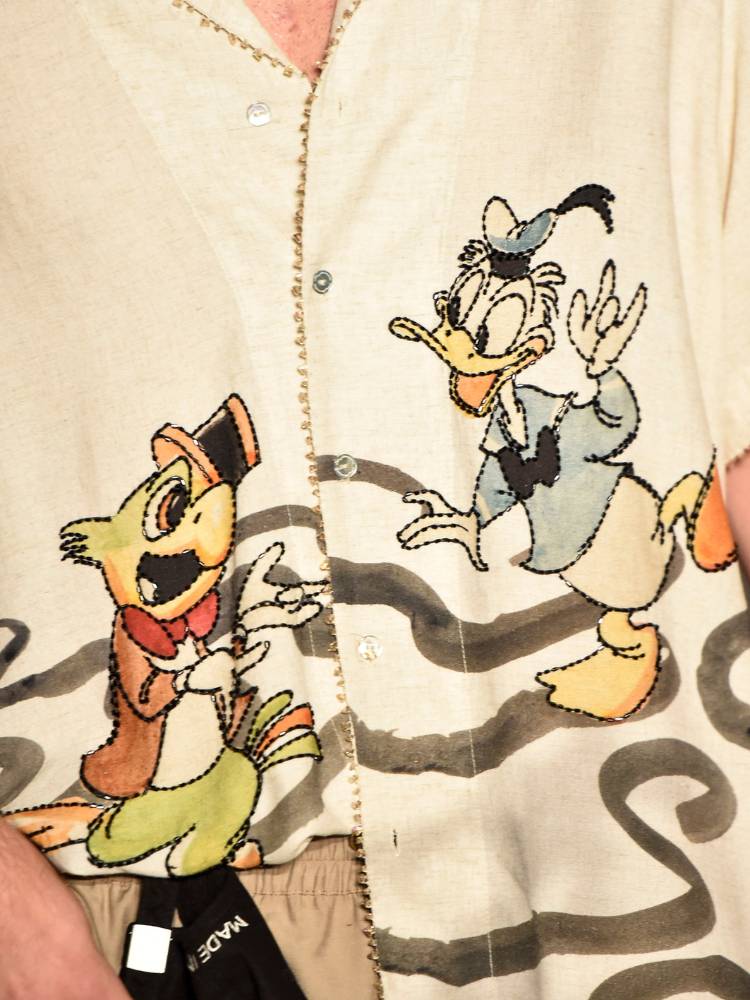 Zoom em camisa bege com estampa do Zé Carioca e Pato Donald