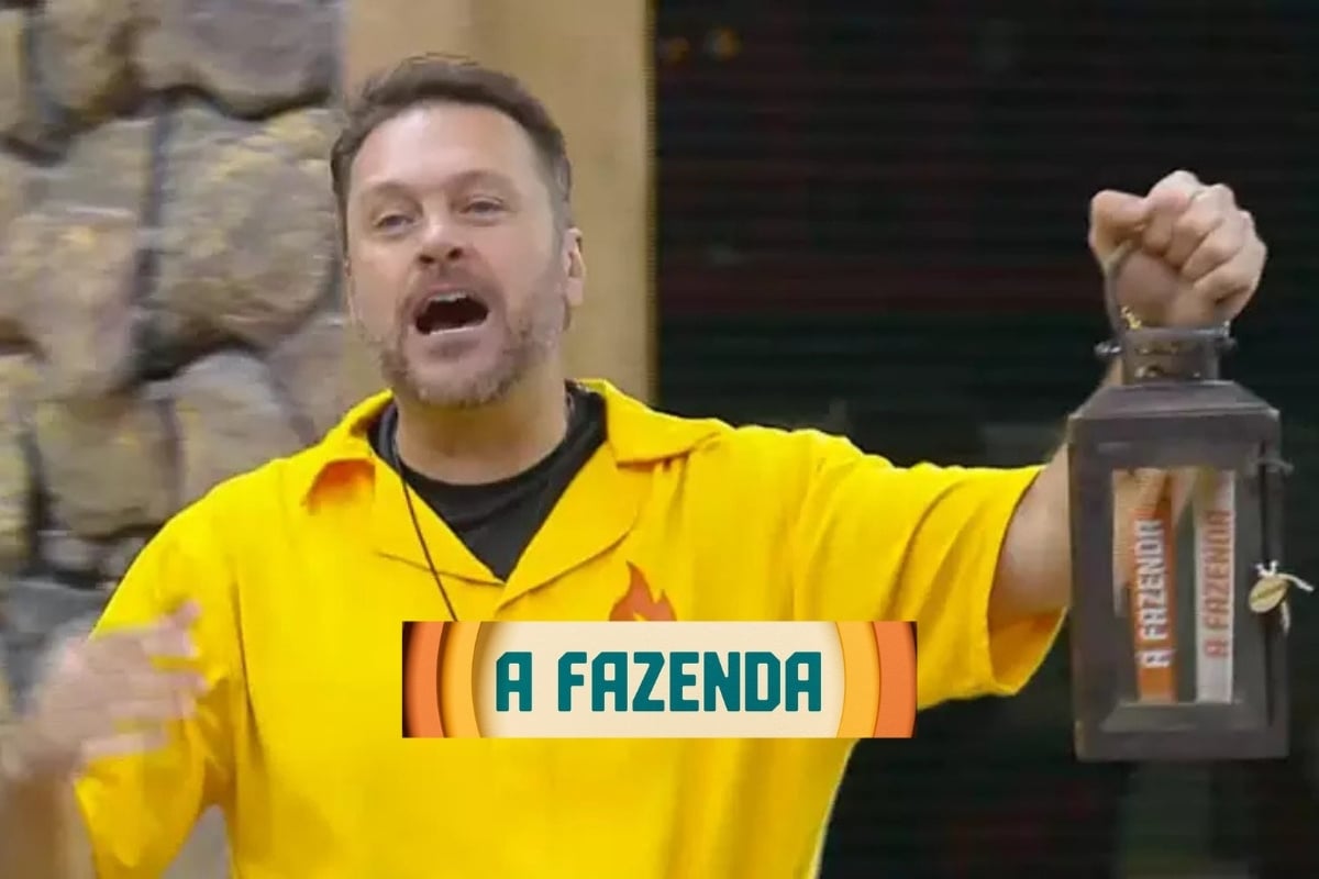 Um participante de A Fazenda 16 segura o Lampião, símbolo de poder no reality show. Ele veste uma camisa amarela e está em um cenário de pedras, expressando entusiasmo. O logotipo do programa, "A Fazenda", aparece em destaque na imagem.