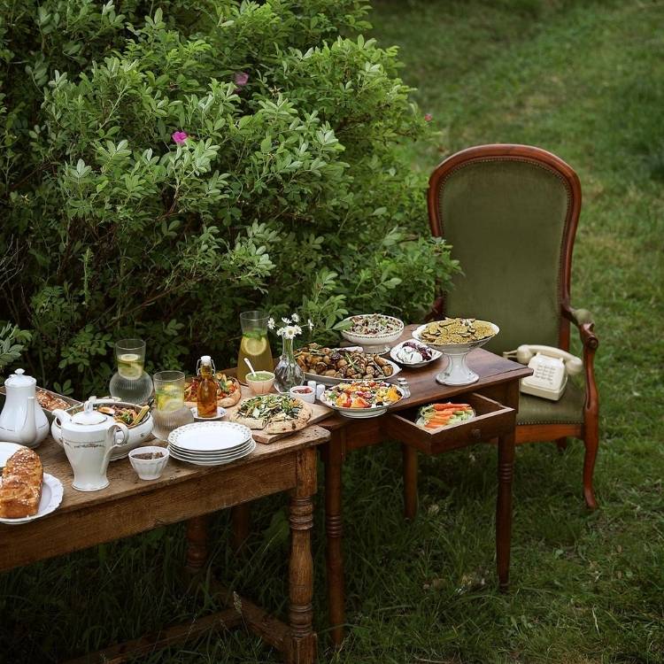 Mesa posta ao ar livre, com comidas de brunch e cadeira de madeira 