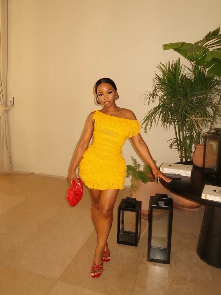 Mulher de pele negra usando vestido curto amarelo com acessórios vermelhos