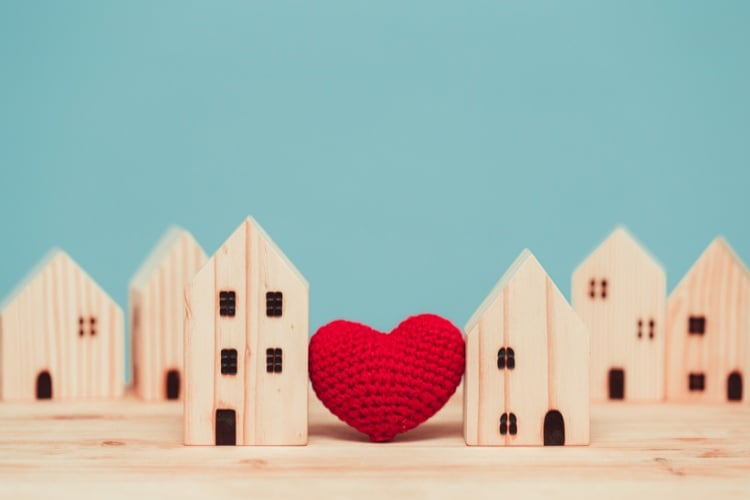 Foto de fundo verde água de casas de brinquedo de madeira com um coração de artesanato entre duas casas 