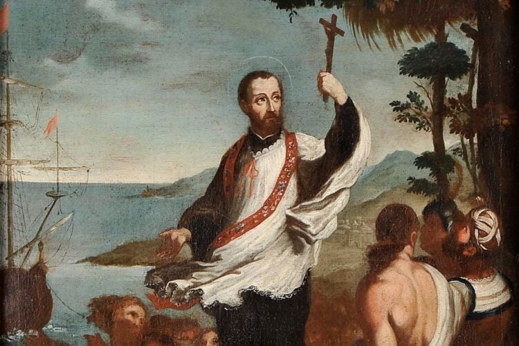 A imagem mostra São Francisco Xavier pregando, vestindo uma túnica branca e estola ornamentada. Ele segura uma cruz no ar com a mão direita, enquanto uma multidão o observa com atenção. Ao fundo, há um navio no mar e uma paisagem montanhosa, ressaltando seu papel como missionário viajante.