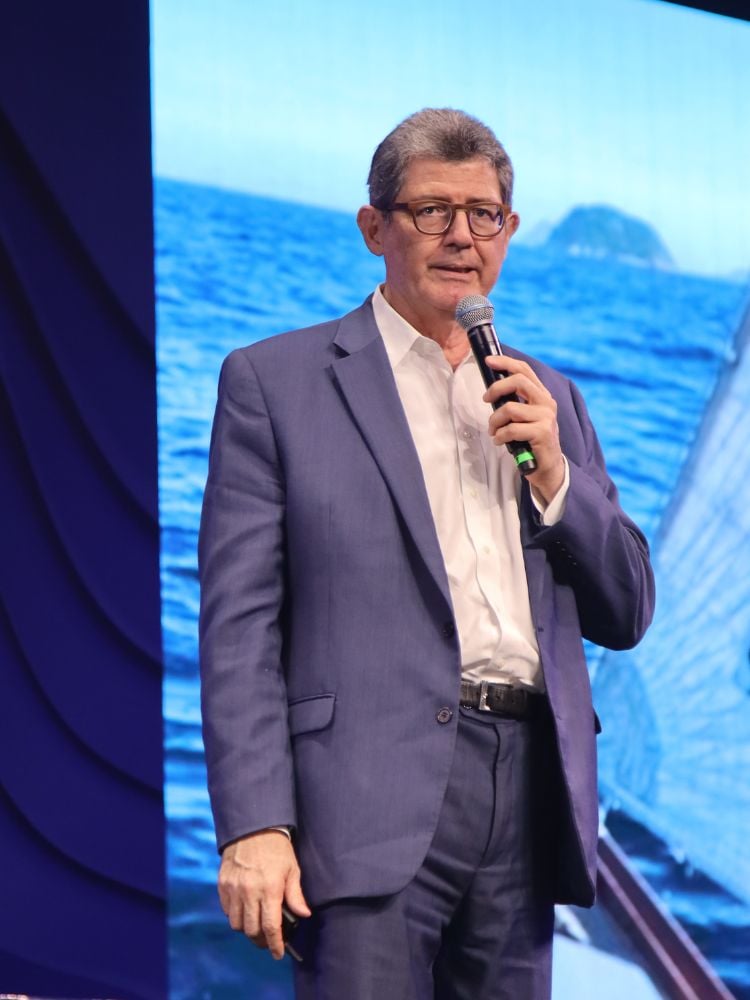 Joaquim Levy usando terno azul e camisa branca enquanto fala ao microfone 