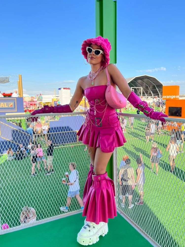 Jess em festival de música usando look rosa composto por bucket hat, corset, saia, barra, bolsa e tênis branco