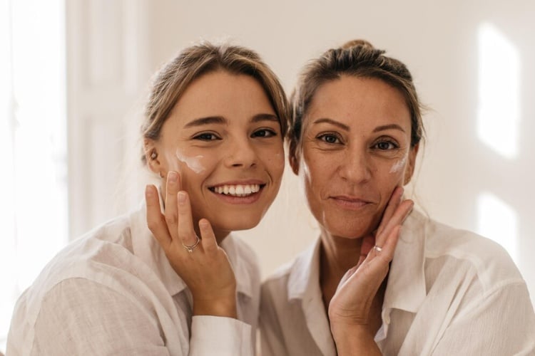 Mãe e filha usando pijama claro e fazendo skincare juntas 