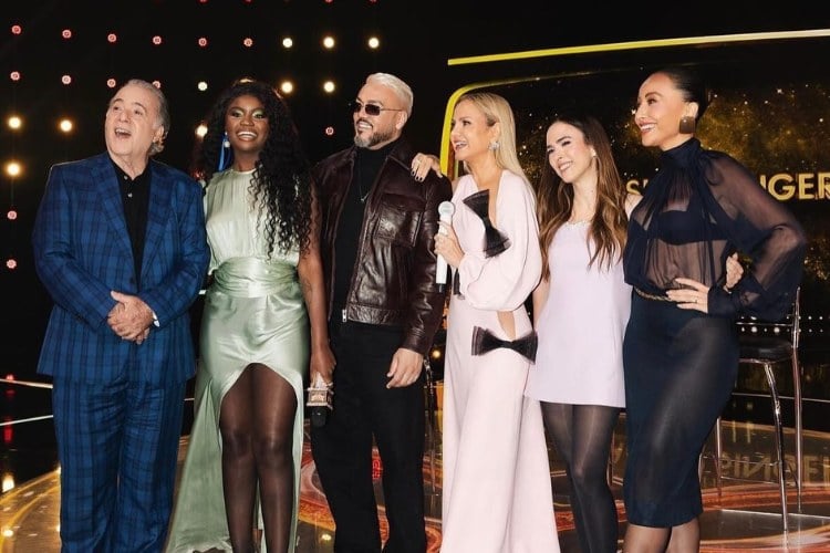 Tony Ramos, Kenya Sade, Belo, Eliana, Tata Wernwck e Sabrina Sato abraçados no palco do The Masked Singer Brasil