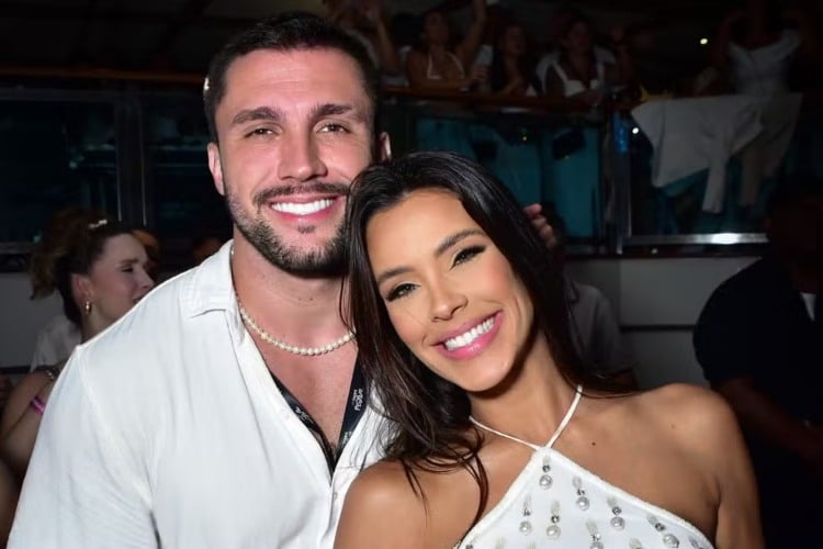 Imagem mostra o casal de ex-BBBs Arthur e Ivy Moraes sorridentes e usando roupas claras.