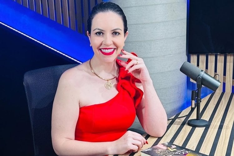 Foto de Aline Kummer usando blusa vermelha de um ombro só em podcast sobre como transformar seus sonhos em metas diárias