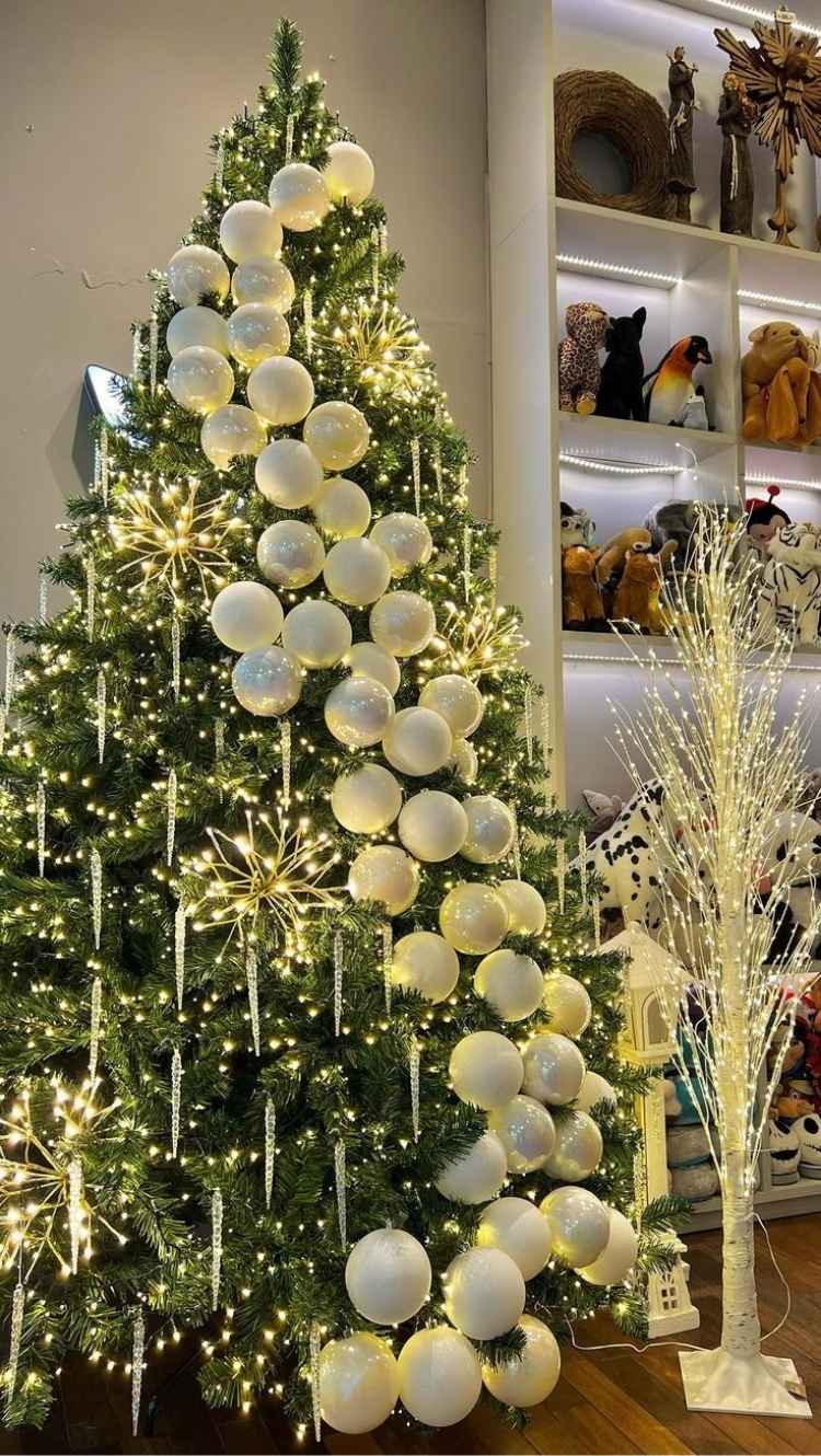 Foto de árvore de Natal verde com pisca-pisca diferente e bolas brancas dispostas em formato de festão