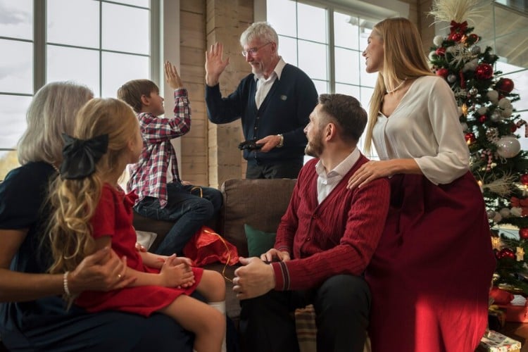 Foto de família de pele clara no Natal com criança fazendo hi-five com idoso