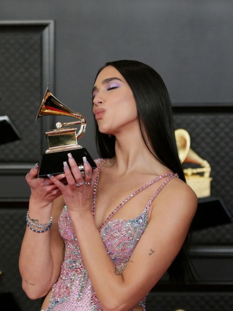 Dua Lipa usando vestido furta-cor e quase beijando prêmio do Grammy