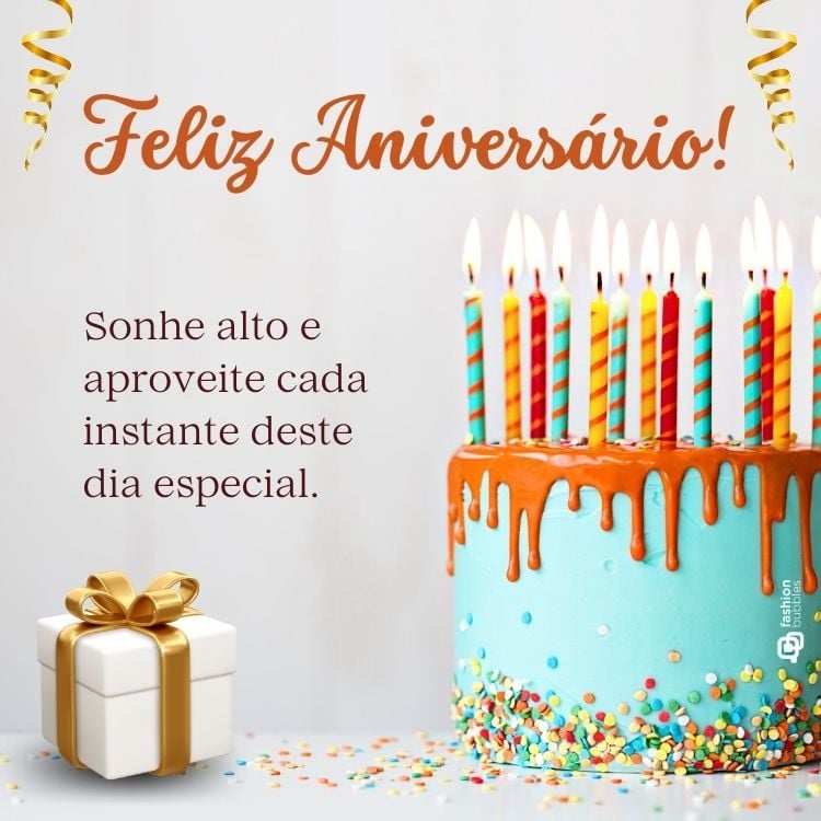 A imagem mostra um bolo azul com cobertura laranja escorrendo e velas listradas acesas no topo. Ao lado, um presente com laço dourado e a mensagem "Feliz Aniversário! Sonhe alto e aproveite cada instante deste dia especial." Confetes coloridos decoram o fundo.