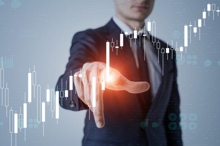 A imagem mostra uma pessoa de terno tocando gráficos financeiros digitais, destacando barras de velas. A cena simboliza análise de mercado e uso de tecnologia em finanças, representando controle e previsão em investimentos com um toque futurista e inovador.