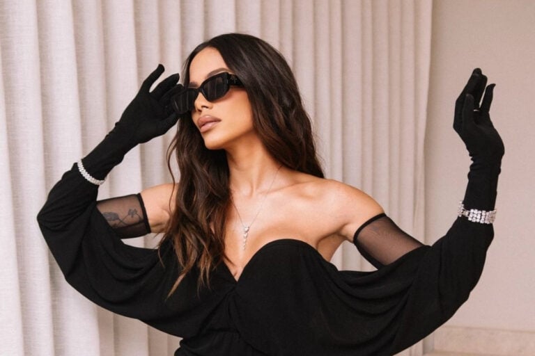 Anitta de vestido preto e óculos de sol em fundo de cortina para o Prêmio Multishow 2024