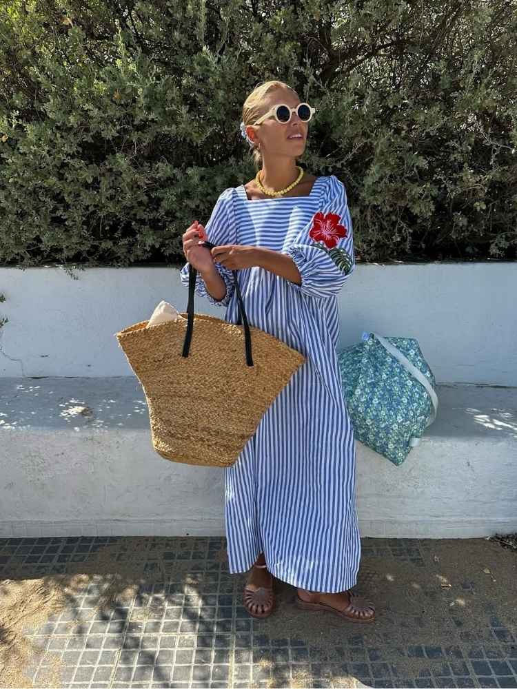 Mulher loira usando vestido listrado azul e branco com jelly shoes dourado, uma das tendências de sapato para o verão 2025