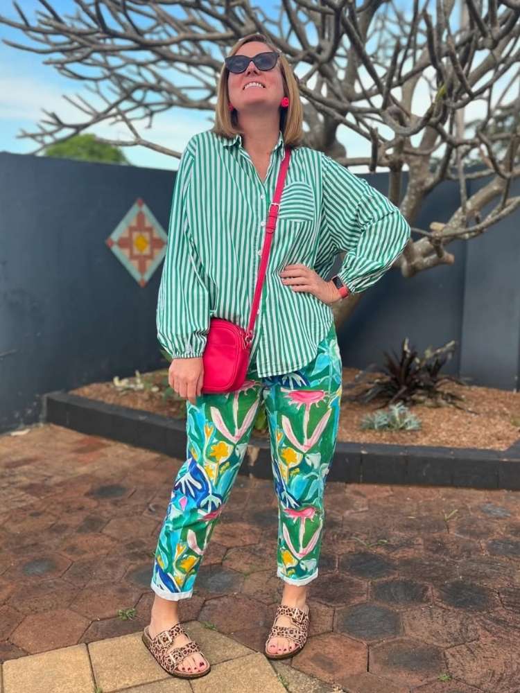 Mulher usando look de verão 2025: camisa listrada verde, calça estampada e sandália birken de oncinha